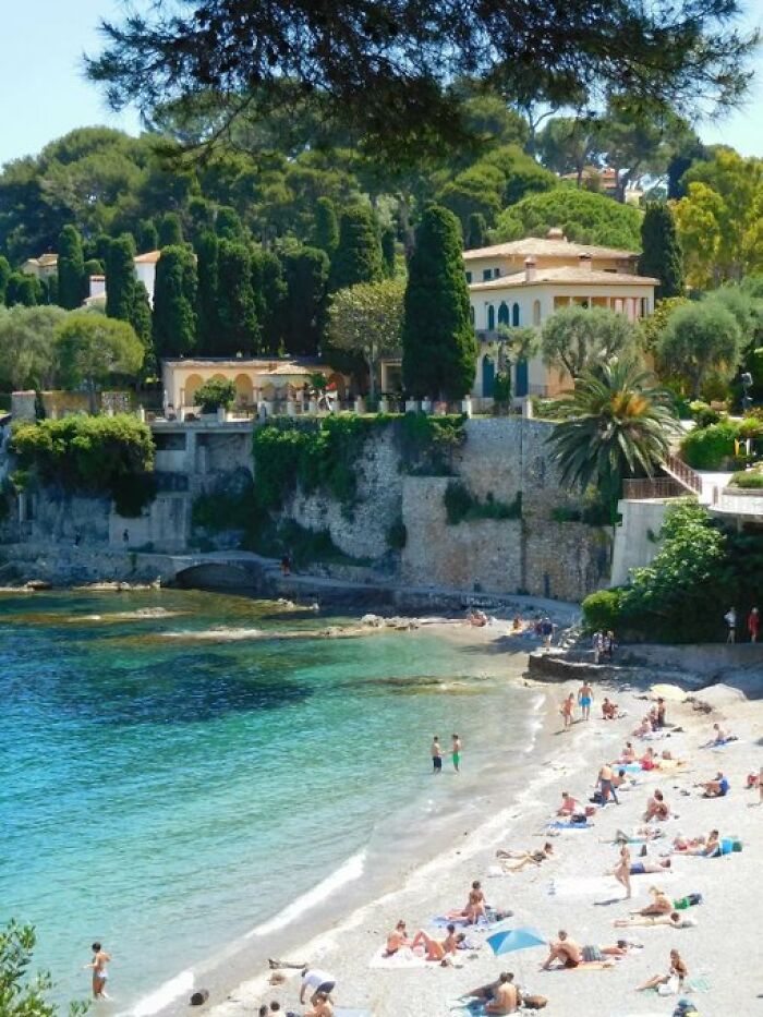 Beautiful coastal scene with people relaxing on a sandy beach, overlooked by elegant buildings with so much character.