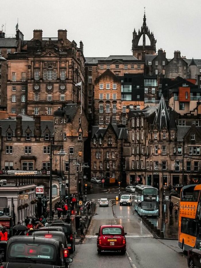 A busy cityscape with historic buildings with character and a mix of old and new architecture under a cloudy sky.