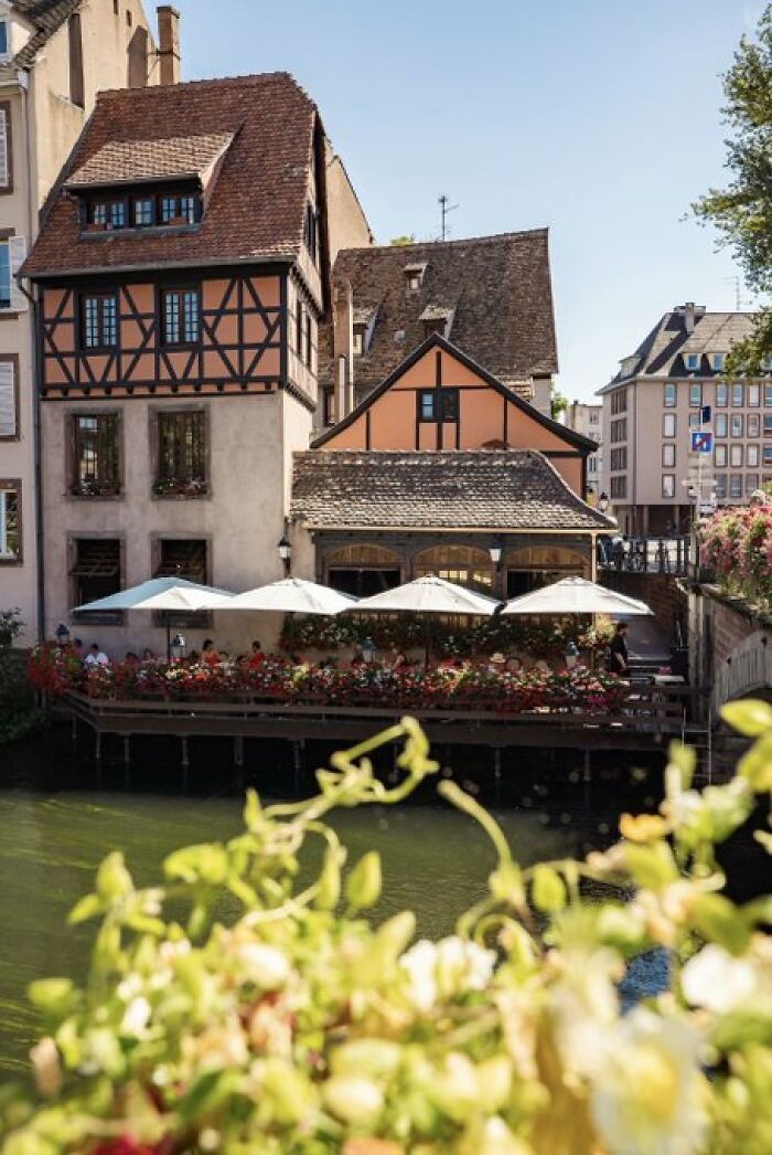Charming, half-timbered buildings with character and a waterside restaurant patio adorned with flowers.