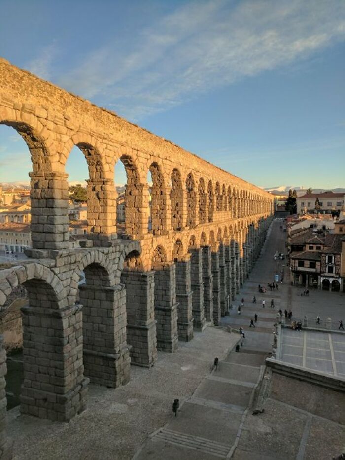 A grand ancient Roman aqueduct with numerous arches stretching across a town, an impressive building with character.