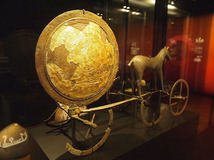 The Trundholm Sun Chariot, a bronze age historical artifact featuring a golden sun disk and horse sculpture.