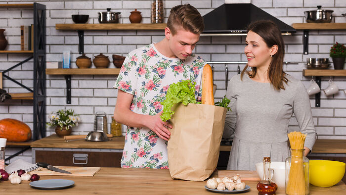 A couple unpacking groceries in a kitchen, contemplating divorce papers and why they signed them.