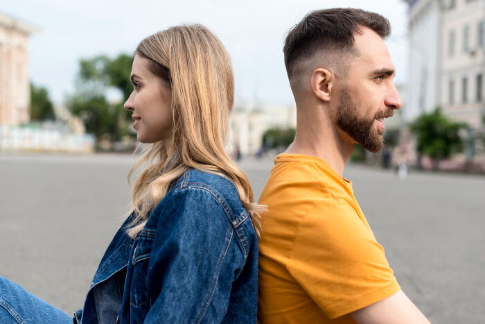 A man and a woman sitting back to back, illustrating the concept of divorce papers and not fighting harder.