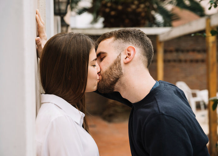 A man and a woman sharing a passionate kiss, leaning against a wall. They are not fighting hard but are in love, avoiding divorce papers.