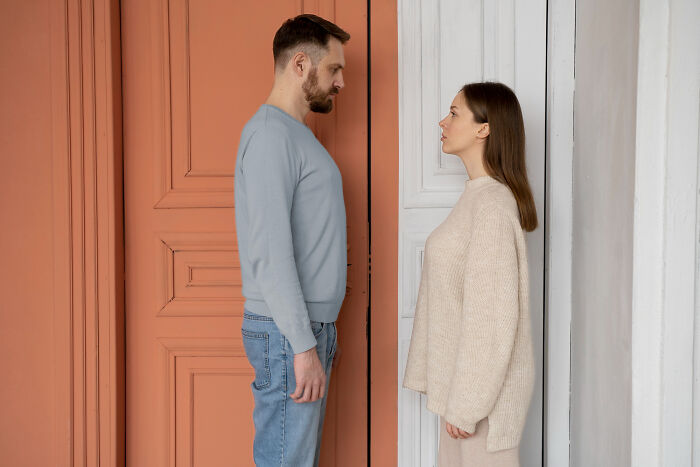 A man and woman stand facing each other, contemplating why they signed divorce papers.