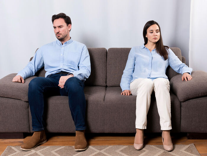 A man and woman sit separately on a couch, reflecting on why they signed divorce papers.
