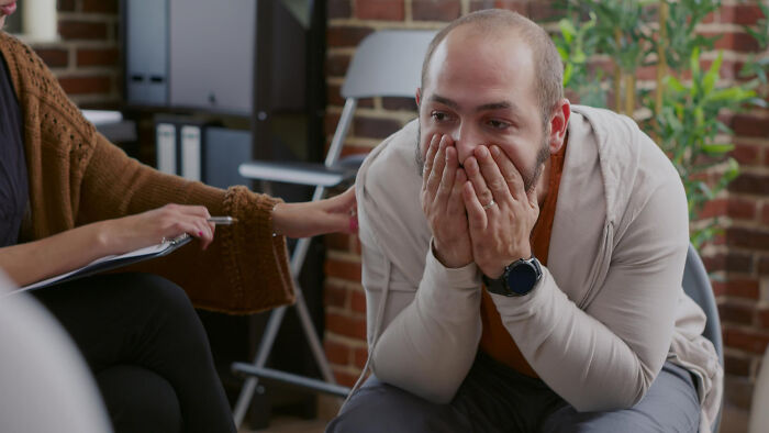 A man crying at a support group, revealing the emotional toll of divorce on men.