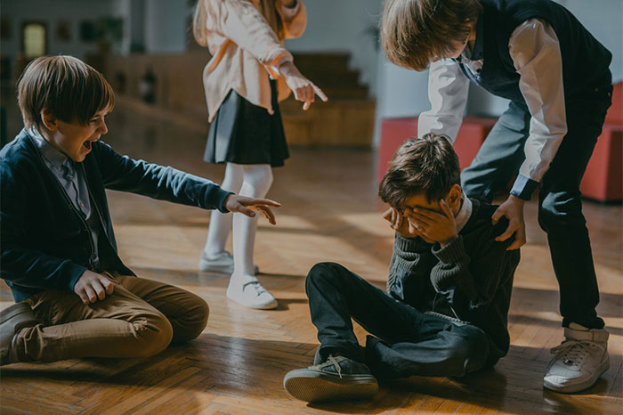 A group of kids bully a crying kid on the floor, gaslighting him. A group of kids bully a crying kid on the floor, gaslighting him.