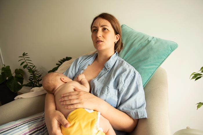 A mother breastfeeding her baby, highlighting the personal space and challenges with MILs.