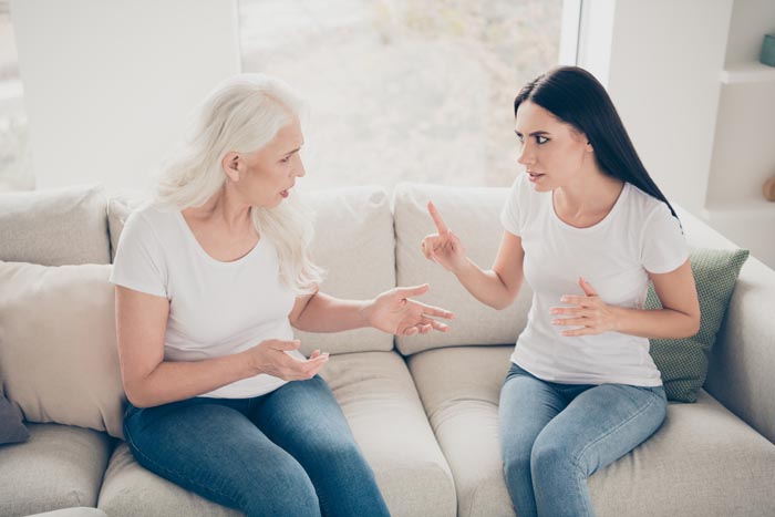 Two women, one older and one younger, arguing on a couch, showing difficult MILs.
