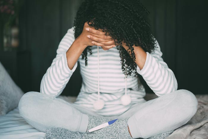 A distressed woman with a pregnancy test, illustrating MILs and challenging family dynamics.