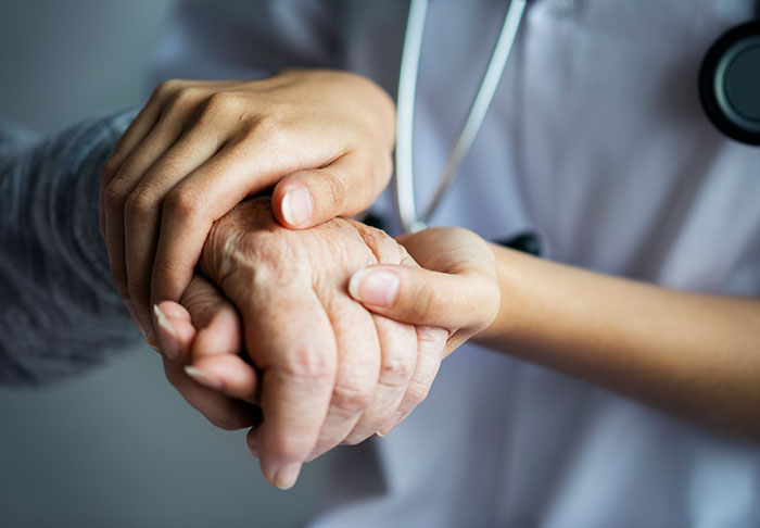 A nurse holding an elderly patient's hand, showing empathy for patients who said weird things.