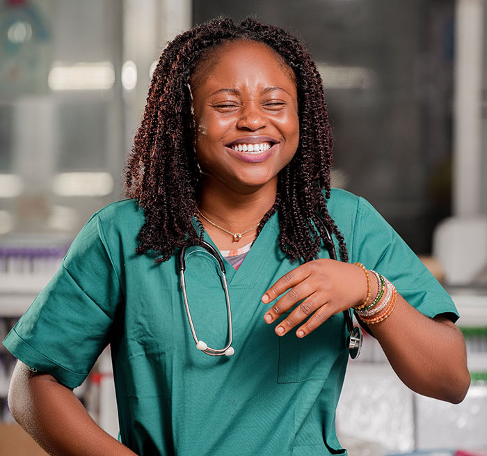 A joyful female medical professional in green scrubs, laughing heartily. Patients said weird things.