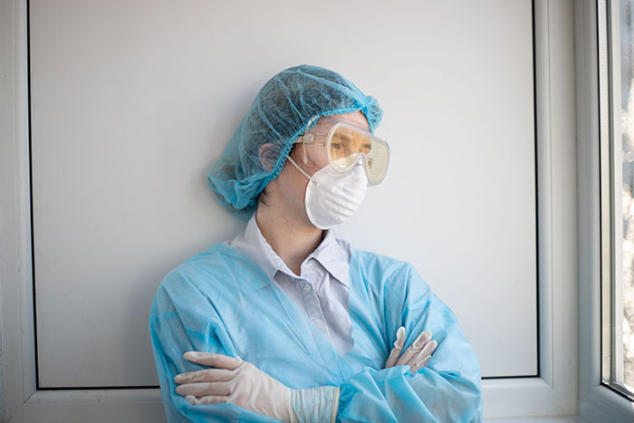 A healthcare worker in PPE, including a mask and goggles, looking stressed, illustrating patients said weird things.