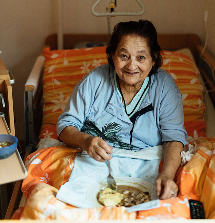 An elderly patient in bed eating, illustrating one of the many patients who said weird things unprovoked.