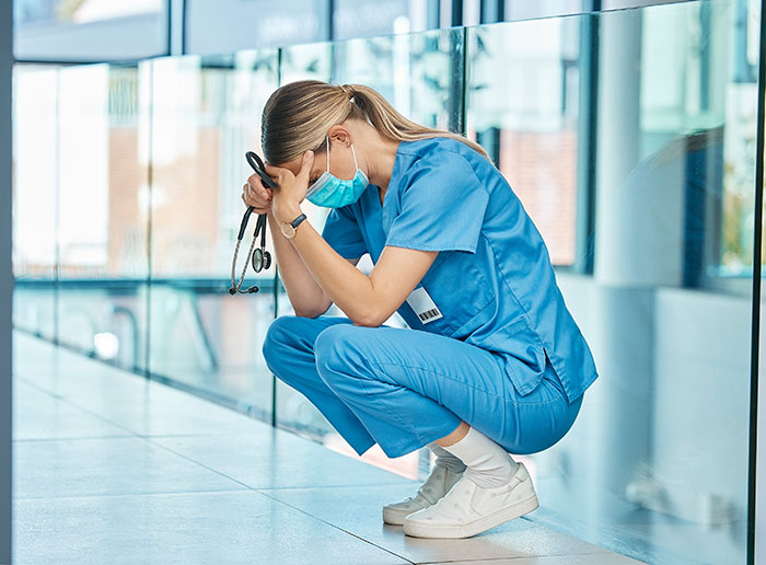 A female nurse in scrubs, looking stressed, symbolizing the reactions to patients saying weird things.