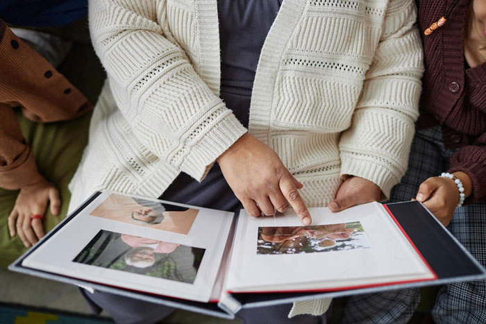 A woman points at photos in an album; wedding photos of the bride and groom. A woman points at photos in an album; wedding photos of the bride and groom.