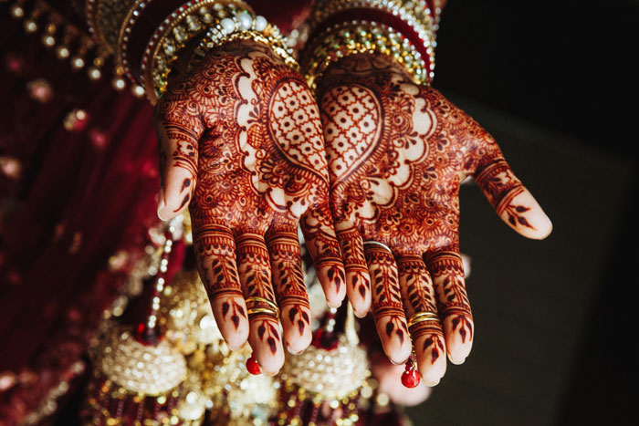 A bride's hands adorned with intricate henna designs for her wedding, showing detailed patterns and jewelry. A bride's hands adorned with intricate henna designs for her wedding, showing detailed patterns and jewelry.
