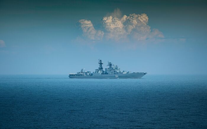 A large warship sailing on a calm blue sea under a cloudy sky, symbolizing the unsolved mysteries of WWII at sea.