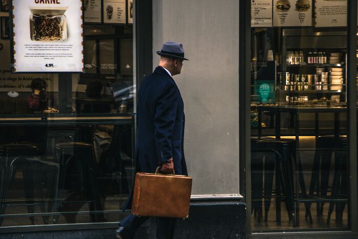 A man in a fedora and coat carrying a briefcase, representing an intriguing mystery from WWII.