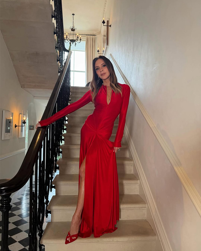Victoria Beckham in a stunning red gown posing elegantly on a grand staircase at a wedding. Victoria Beckham in a stunning red gown posing elegantly on a grand staircase at a wedding.