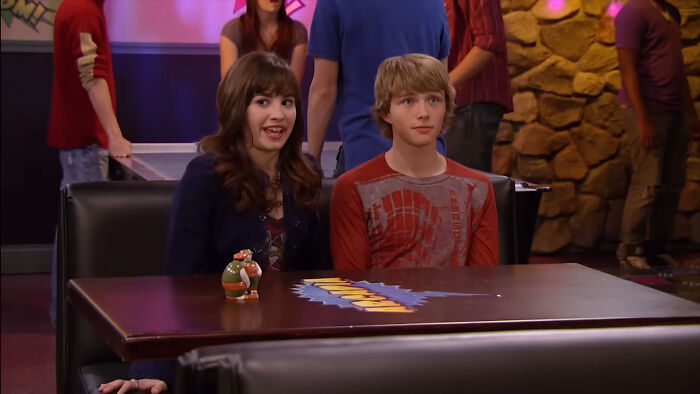 A young Disney heartthrob sitting next to Demi Lovato, looking recognizable from their earlier career.