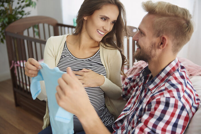 A pregnant woman and a man looking at a baby item, related to difficulty to pronounce a common name. A pregnant woman and a man looking at a baby item, related to difficulty to pronounce a common name.