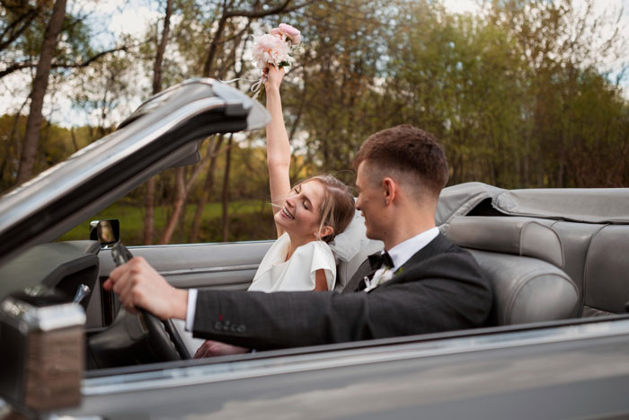 A happy couple driving a convertible car, representing the start of their wedding day across LA.