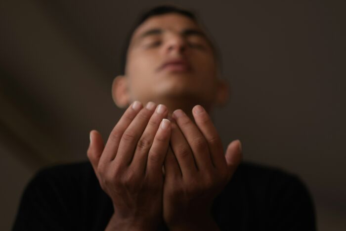 A person with eyes closed and hands open in prayer, evoking the idea of tried to pray away ADHD.