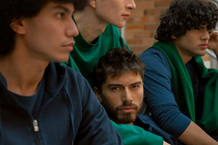 A group of young men, one looking directly at the camera, signifying people who escaped cults and their stories.
