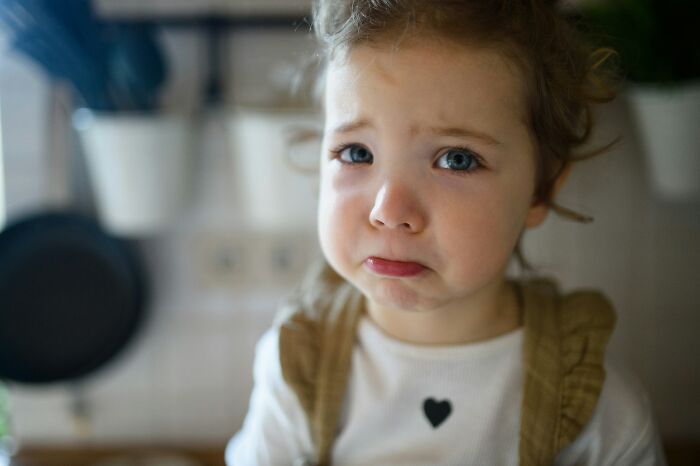 A sad child with tears in their eyes, reflecting the emotional impact of escaping cults and disturbing things.