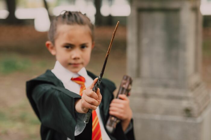 A young child dressed as a wizard, holding a wand, symbolizing the escape from disturbing things in cults.