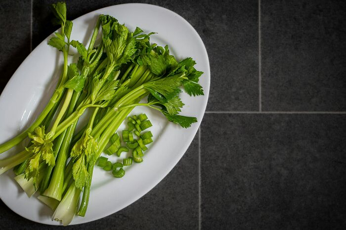 Fresh green celery stalks and chopped pieces on a white plate, unrelated to the topic of tried to pray away ADHD or escaping cults.
