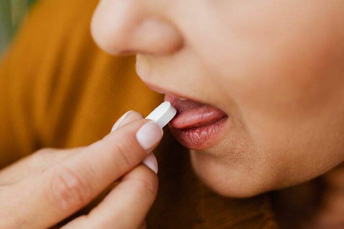 A close-up of a person taking a pill to manage their ADHD symptoms, escaping cults.