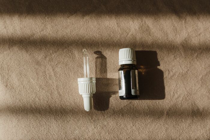 A dropper and a small bottle of medicine or essential oil on a beige surface, representing the search for relief from ADHD.