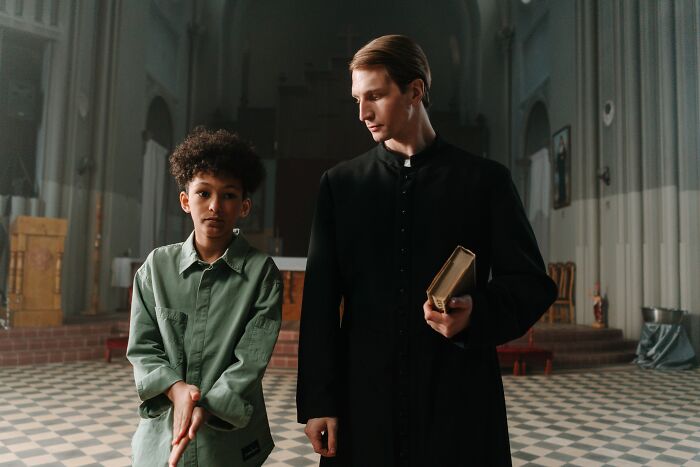 A priest and a young boy standing in a church, symbolizing the experiences of cults and praying for ADHD.