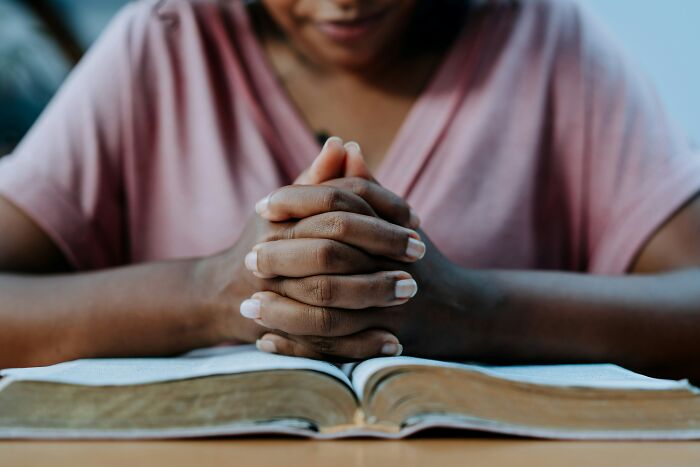 A person with clasped hands, praying over an open book, reflecting the theme of tried to pray away ADHD.