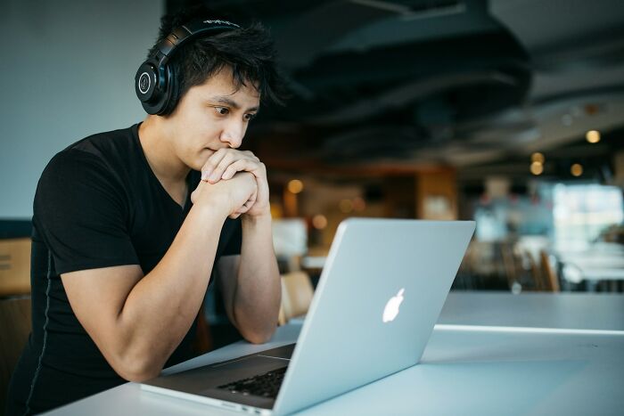 College life freedom: Student with headphones focused on a laptop, reflecting the academic freedom of college life.