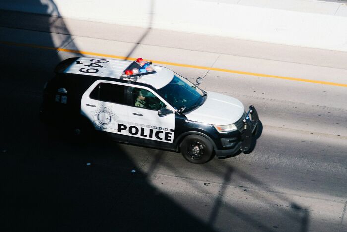 A police SUV with flashing lights on a highway underpass, illustrating work drama stories in an office environment.