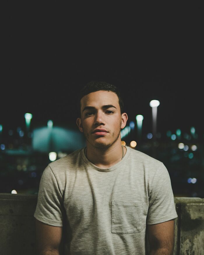 College life: A young man standing at night, bokeh lights in the background, representing the newfound freedom of college life.