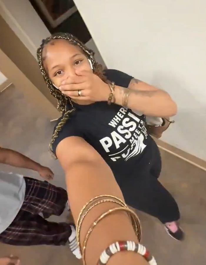 A Black hairstylist looking surprised, covering her mouth, with part of another person visible. A Black hairstylist looking surprised, covering her mouth, with part of another person visible.