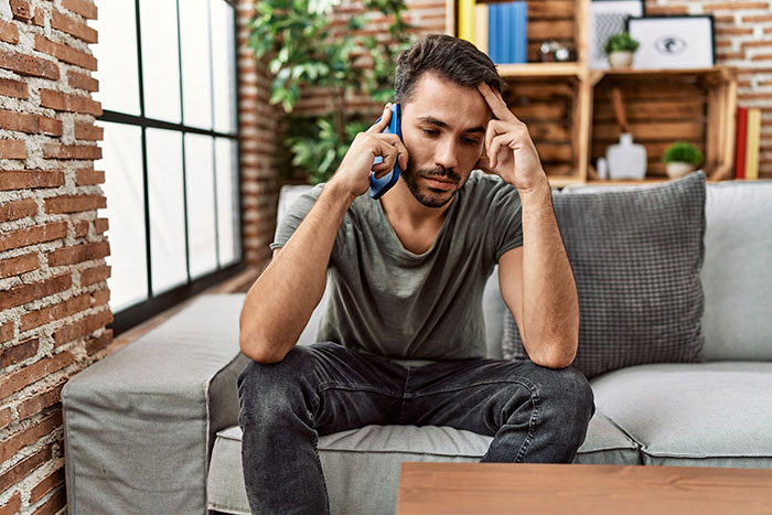 A man looking stressed while on the phone, reflecting the husband's feelings about his wife's secret conversations. A man looking stressed while on the phone, reflecting the husband's feelings about his wife's secret conversations.