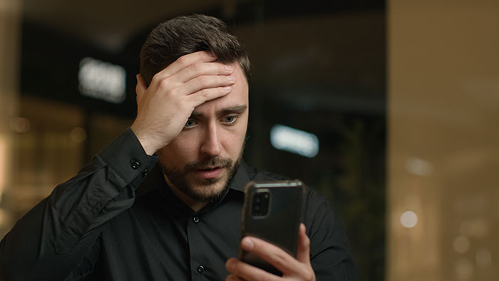 A man looking shocked while holding a phone, reacting to his wife's secret conversations with another guy. A man looking shocked while holding a phone, reacting to his wife's secret conversations with another guy.