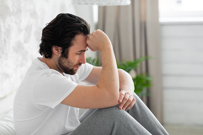 A man looks distraught, contemplating his wife's secret conversations with another guy. A man looks distraught, contemplating his wife's secret conversations with another guy.
