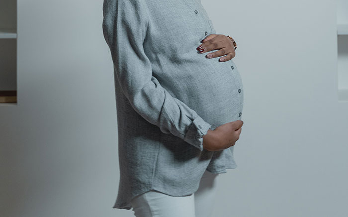 A pregnant woman holds her baby bump, reflecting on her husband's old messages. A pregnant woman holds her baby bump, reflecting on her husband's old messages.