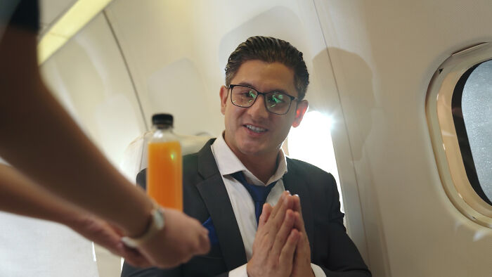 A man in a suit on a plane receiving a drink, ready with an epic comeback.