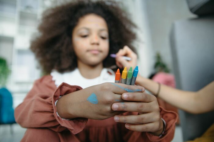 A young girl with paint on her face and hands holds crayons. Epic comebacks can be as colorful as art.