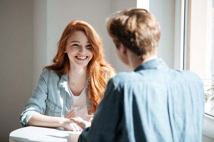 A woman with red hair smiles broadly at a man across a table. This happy moment is like an epic comeback.
