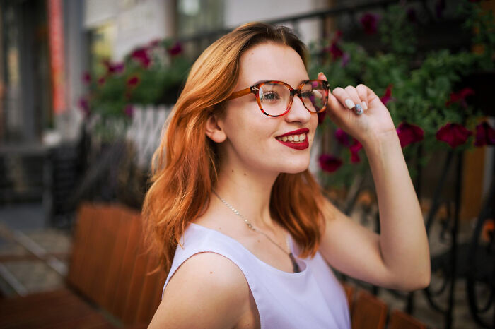 A red-haired woman with glasses, smiling confidently, perhaps after an epic comeback.