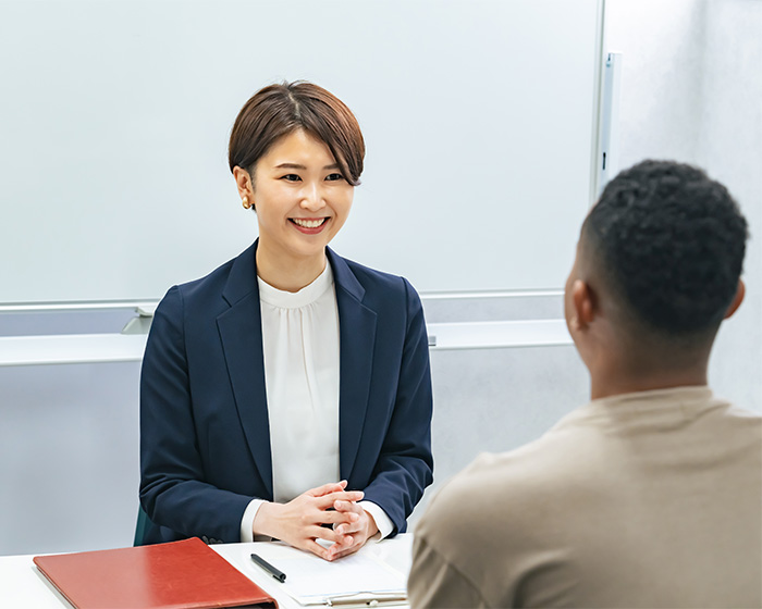 A smiling woman in a suit, sitting across from a man, illustrating a successful resume botoxing trick interview.